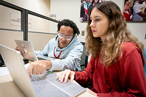Two people collaborating on laptops at a table.